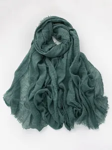 Detail of dark teal linen scarf featuring natural crinkled texture and frayed edges