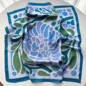 Macro detail of silk-like scarf featuring blue and green abstract floral leaf patterns