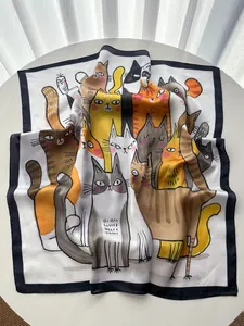 Détail d'un foulard en soie avec imprimés de chats mignons sur une table blanche