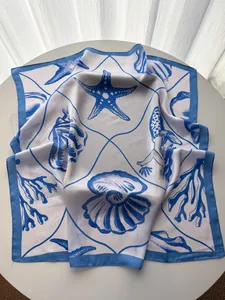 Detail of nautical starfish and seashell print on a white silk-feel square scarf