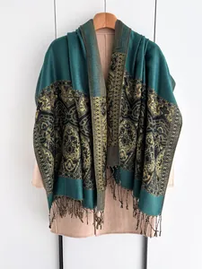 Detailed macro view of dark green and gold ethnic jacquard shawl with tassel edges