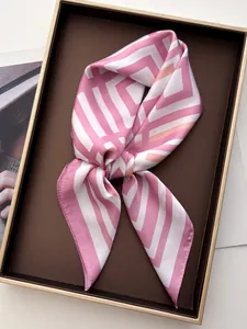 Dettaglio di un foulard in seta rosa e bianca annodato in una scatola da regalo
