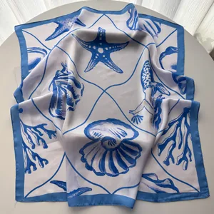 Detail of silk-like square scarf featuring blue starfish and seashell ocean patterns