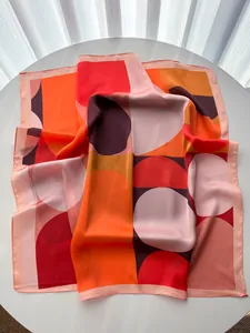 Macro detail of silk-like square scarf featuring bold abstract geometric orange patterns