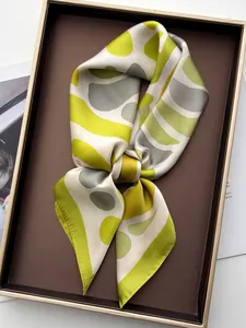 Detail of silk scarf with green geometric pattern in premium brown gift box