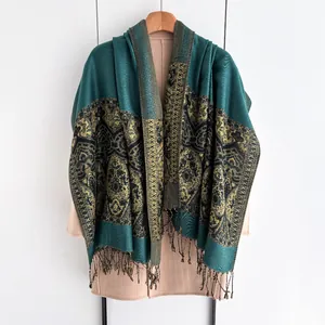 Close-up of deep teal and gold jacquard weave pattern on a thick ethnic shawl with black fringe