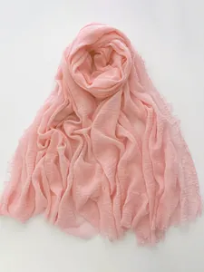 Detail view of light pink cotton linen scarf featuring a pleated texture and frayed edges