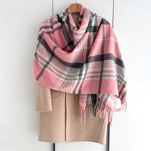 Détail de l'écharpe à carreaux rose et gris avec franges sur un manteau kaki