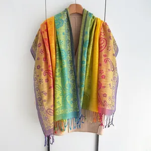 Detail van kleurrijke sjaal met paisley borduursel en regenboogverloop met franjes