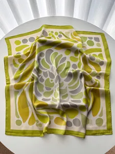 Detailed macro view of geometric pattern silk scarf showing satin texture and rolled edges