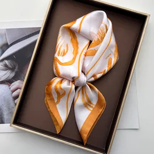 Detailed view of silk square scarf with orange floral print in premium gift box
