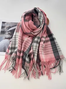 Détail d'une écharpe d'hiver à carreaux roses et gris avec des franges douces