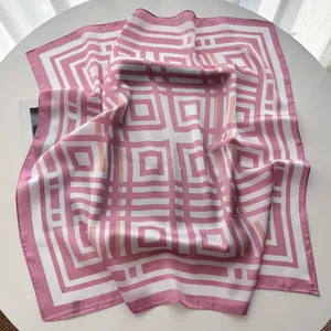 Dettaglio di un foulard di seta geometrico rosa e bianco con texture satinata