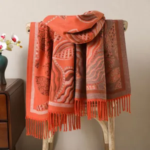 Detailed close-up of orange ethnic jacquard shawl with intricate fringes and patterns