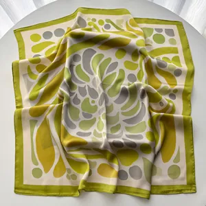 Detail of silk scarf with green and yellow leaf pattern on white table background