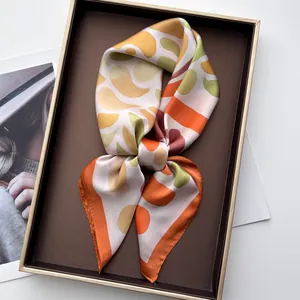 Detail of silk-feel scarf with geometric paisley patterns in a luxury gold-rimmed gift box