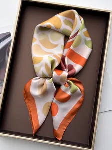 Macro detail of silk-like geometric pattern scarf elegantly placed in a brown gift box
