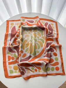 Detailed texture of satin square scarf with abstract geometric patterns in orange and green