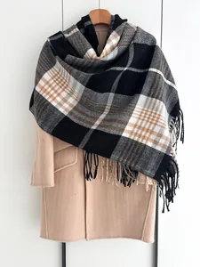 Détail d'une écharpe à carreaux noir et beige avec franges sur manteau en laine