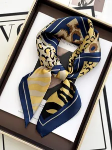 Close-up of a leopard print silk scarf tied in a bow inside a premium gift box
