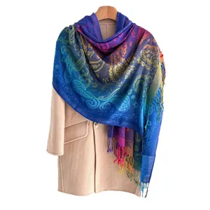 Kleurrijke regenboog sjaal met paisley patroon en kwastjes op beige jas