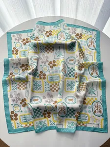 Detail of square silk scarf showing vintage palm tree and sardine motifs on white table