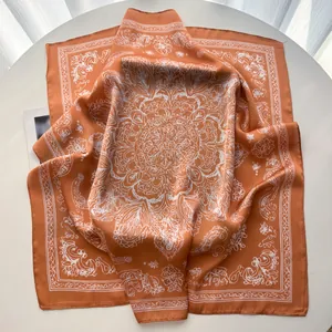 Detail of vintage terracotta silk scarf with white mandala print on a white surface