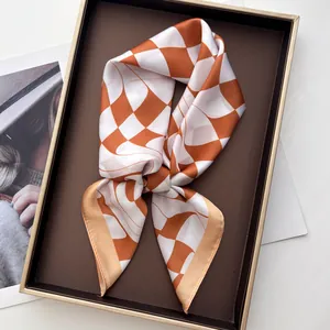 Detailed view of checkered silk scarf in orange and white on a luxury gold tray