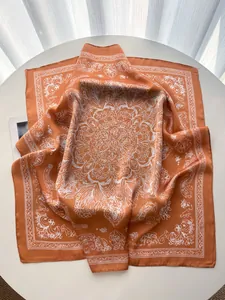 Detail of elegant orange square scarf with white mandala patterns and silky texture