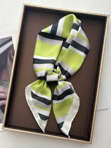 Detail of a silk neckerchief featuring modern green and grey stripes on a tray
