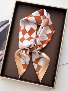 Macro detail of silk scarf with orange twisted checkerboard pattern in a gift box