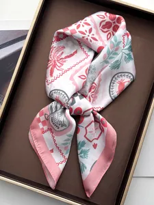 Detail of pink silk square scarf with palm and sardine prints in a gift box
