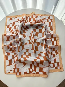 Detail of a geometric checkered silk scarf with brown and white waves on a white table