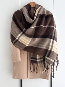 Détail d'une écharpe à carreaux marron avec franges sur un manteau en laine beige