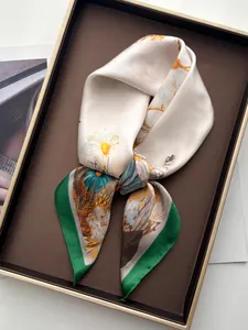 Close-up of a floral silk scarf with daisy patterns tied in a flat knot inside a gift box