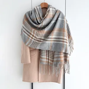 Gros plan d'une écharpe à carreaux douce avec franges sur un manteau de laine chaud
