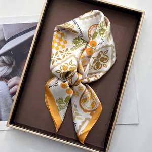 Detailed view of square silk scarf with palm tree and geometric prints on a tray