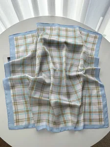 Detail of checkered silk scarf with light blue borders on a minimalist table