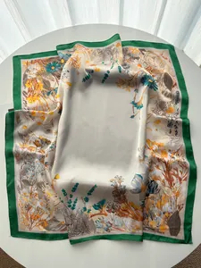 Detailed close-up of floral print silk scarf featuring elegant satin finish and green borders