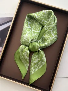 Detail of vintage emerald silk scarf with white floral patterns on a luxury tray