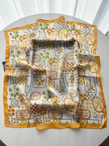 Detail of silk-like satin square scarf featuring palm trees and sardine motifs with yellow borders