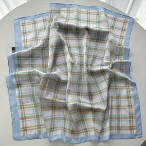 Detailed view of light blue plaid silk square scarf draped on a white round table