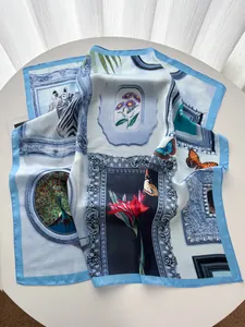 Detailaufnahme des himmelblauen Seidenschals mit kunstvollen Schmetterlings- und Blumenmustern