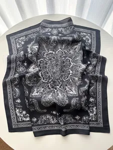 Detailed view of square silk scarf with white mandala patterns on black fabric