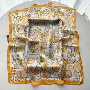 Detailed texture of square silk scarf featuring palm trees and sardine motifs with yellow edges