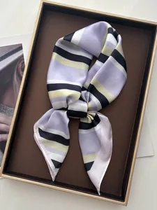 Detailed close-up of a purple and beige striped silk scarf on a luxury display tray