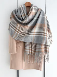 Détail d'une écharpe à carreaux gris et caramel avec franges sur manteau