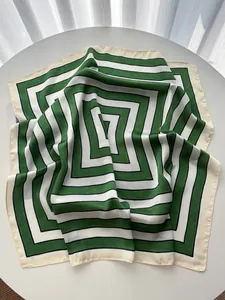 Detailed close-up of a green and white striped silk square scarf with hand-rolled edges