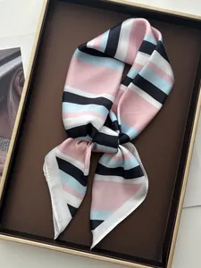 Close-up of a striped silk neckerchief with pink and blue tones on a luxury display tray