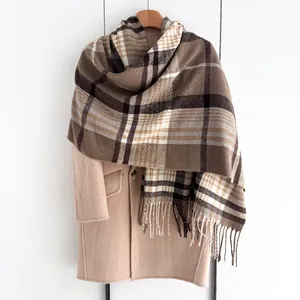 Détail d'une écharpe à carreaux beige et marron avec franges sur un manteau